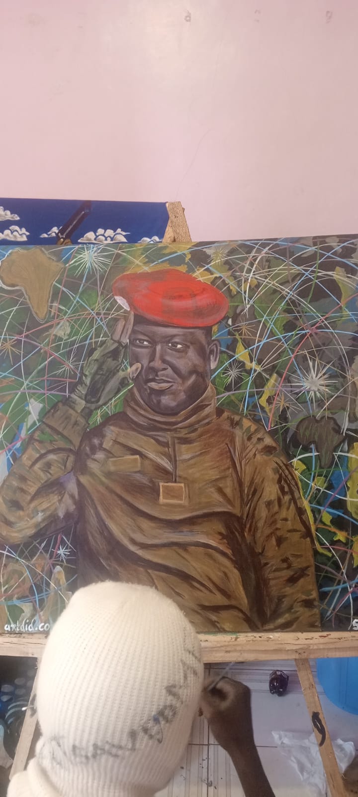 Portrait painting of a figure in a red beret against a starline map of Africa